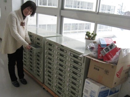 廊下に置いてあるベルマーク整理ケースを見る育友会の東郷祐美学級委員長。一次仕分けは児童が行います=いずれも金沢市の四十万小学校で