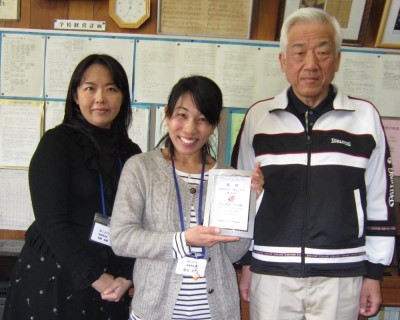 津金校長（右）と、優秀賞の賞状を手に笑顔の堀田委員長。左が副委員長の松廣佐織さん