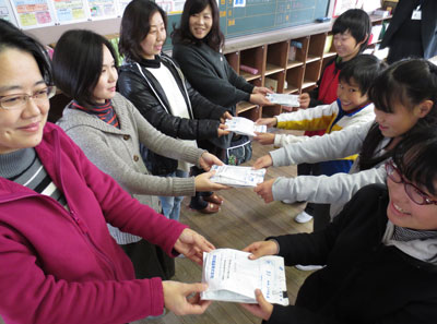 PTA保健福祉委員会の保護者に、仕分けしたベルマークを手渡す児童会委員たち=いずれも愛知県安城市立作野小学校