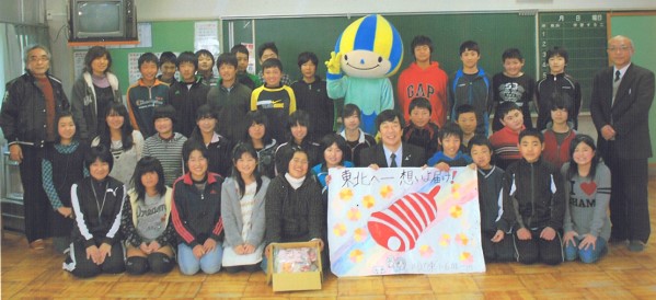 寄せ書きを持つ佐藤川辺町長(前列中央)とミナモ(後列中央)を囲んで記念撮影する6年生。右端は有加校長=岐阜県川辺町の川辺東小学校で(同小提供)