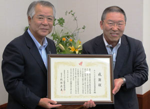 感謝状を受け取るあいおいニッセイ同和損保の鈴木久仁社長（左）。右はベルマーク財団の中島泰常務理事