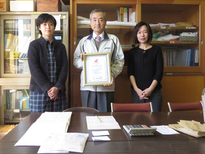 ４００万点達成の感謝状を持つ伊藤校長。左が柴田委員長、右が平間副委員長