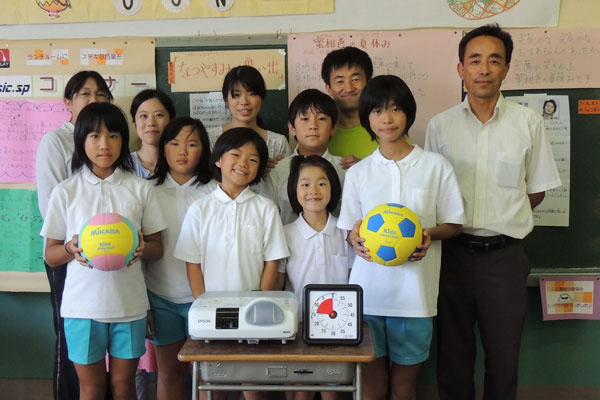 援助品を前に德光校長(右端)や先生たちと記念撮影する子どもたち6人