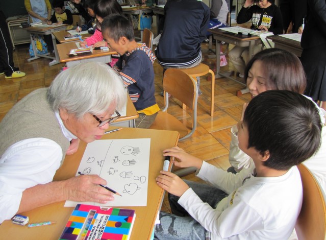 「いいねぇ。もっともっと好きに描いてご覧」と低学年児童にアドバイスする喜多川さん