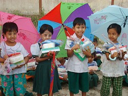傘を広げて、学用品を両手いっぱいに抱え喜ぶ子どもたち