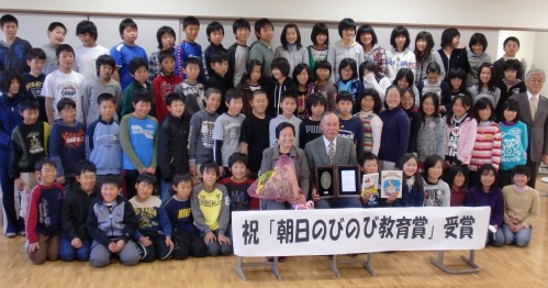 谷口岩雄さん夫妻が、５、６年の児童全員と幅校長（右端）に囲まれて記念撮影
