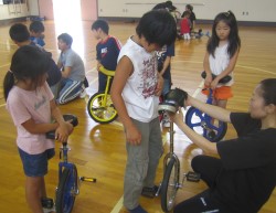 「サドルはおへその高さで」と指導する成田さん=中富良野町立西中小学校体育館で